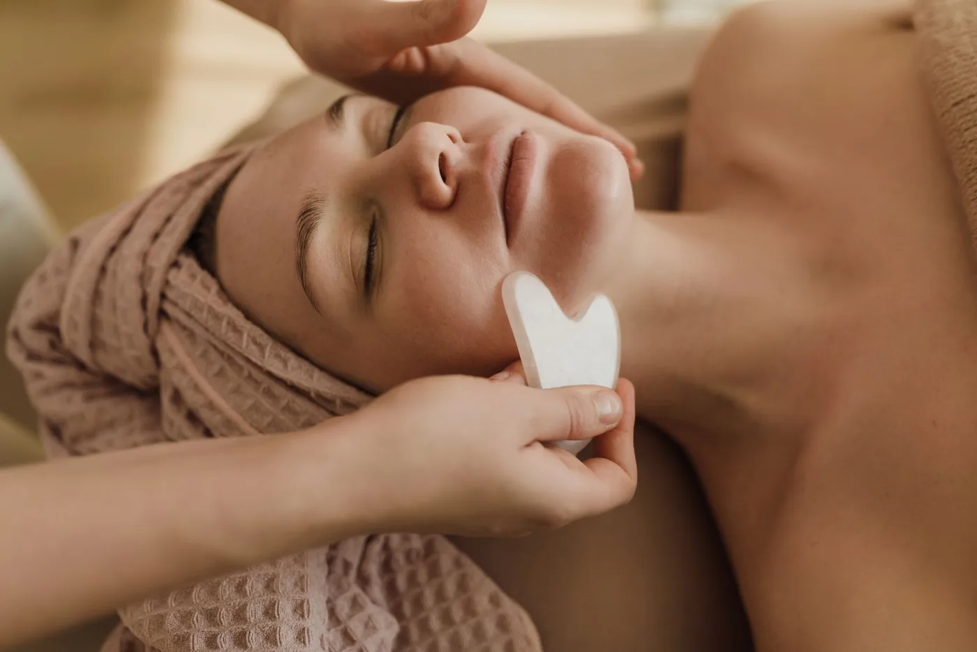 Gua sha face massage with a smooth stone tool during a facial in Muscat