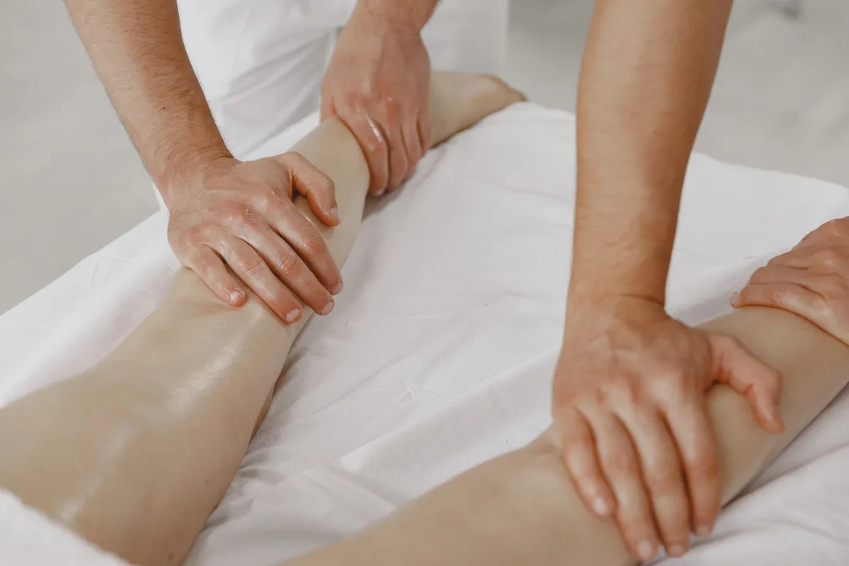 Light, rhythmic lymphatic drainage strokes along the legs during a massage session